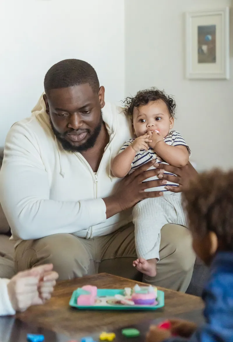 A father playing with his young children at home
