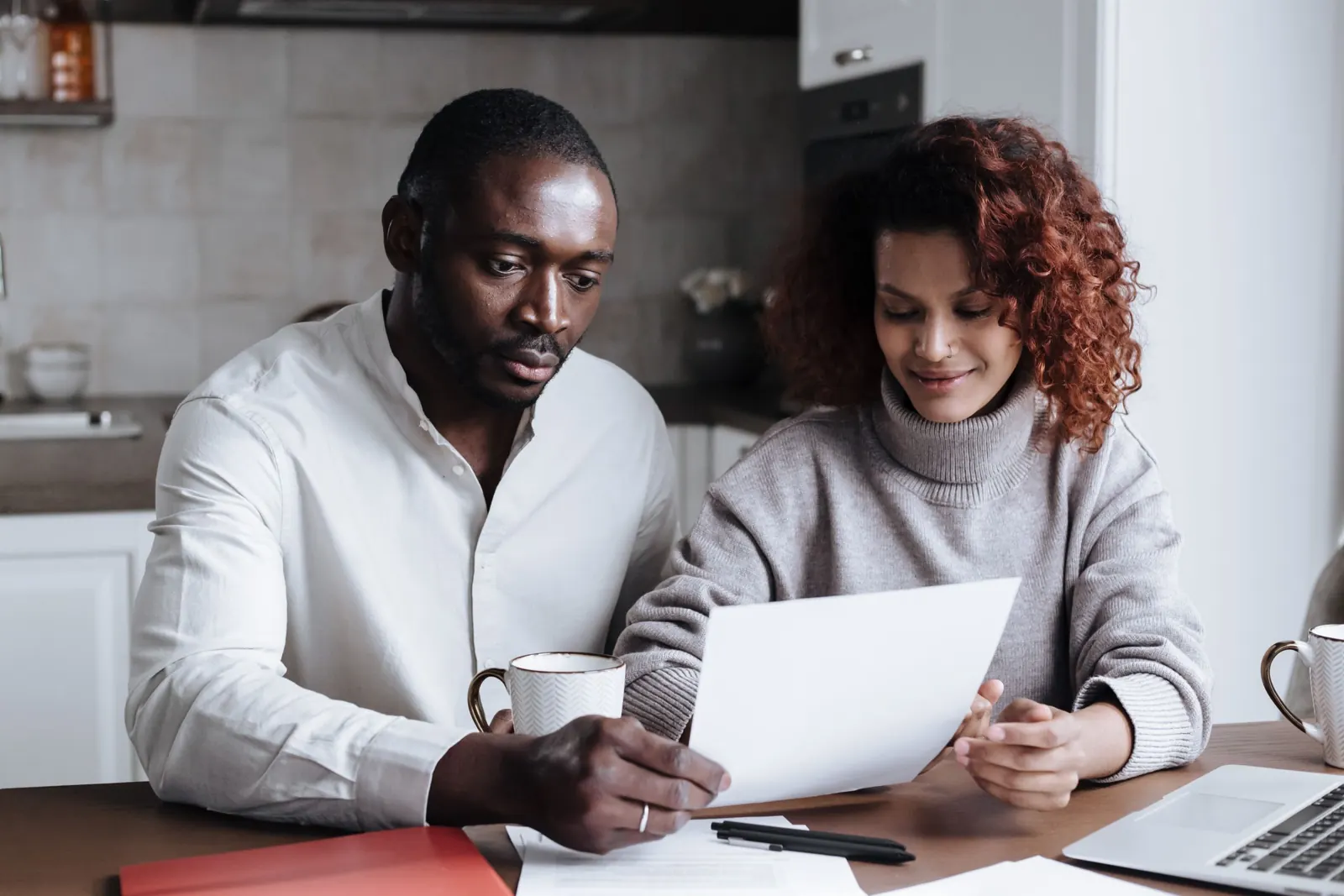 Two people reviewing paperwork together at a kitchen table